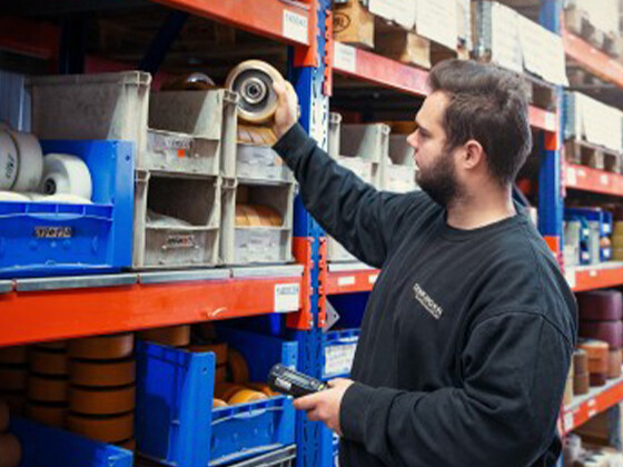 Fachkraft für Logistik und Materialwirtschaft Azubi räumt Materialien in ein Regal und arbeitet an der Lagerorganisation bei Genkinger.