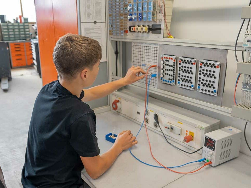 Auszubildender Elektroniker für Betriebstechnik baut einen Schaltkreis am Übungssteckbrett auf.