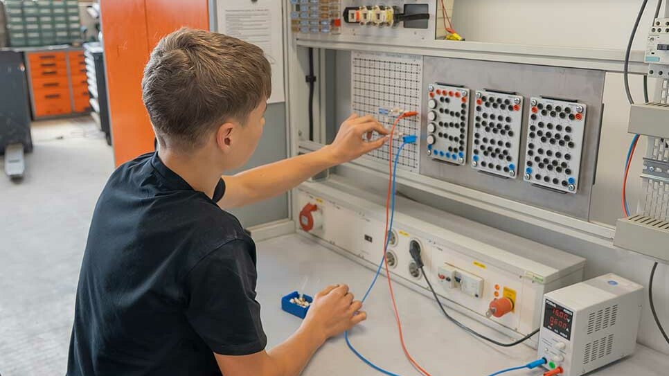 Auszubildender Elektroniker für Betriebstechnik baut einen Schaltkreis am Übungssteckbrett auf.