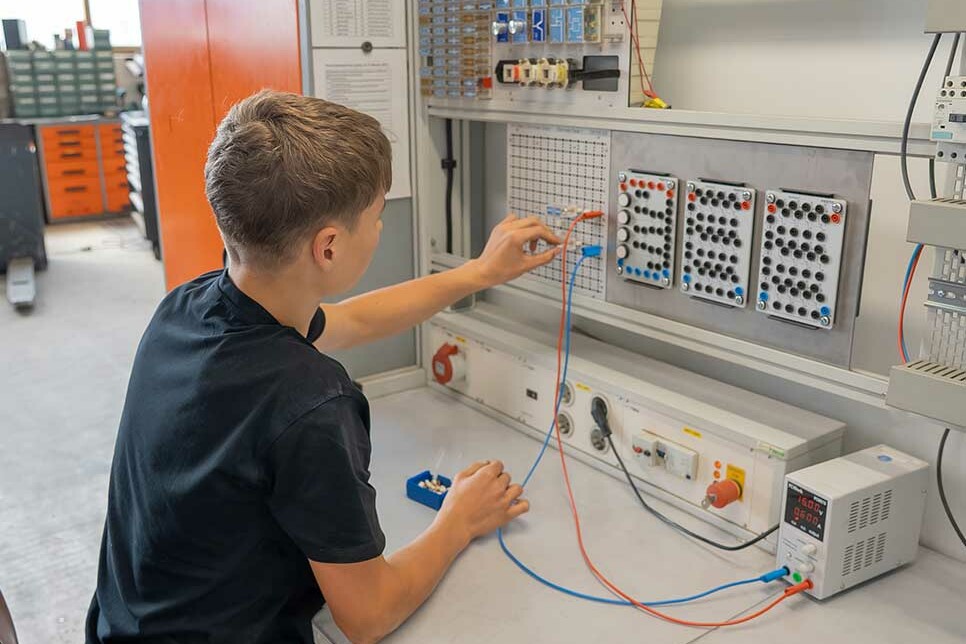 Auszubildender Elektroniker für Betriebstechnik baut einen Schaltkreis am Übungssteckbrett auf.
