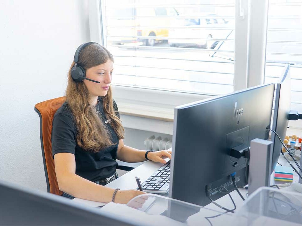 Azubi Industriekaufman: Die Auszubildende Laura von Genkinger telefoniert am Headset und macht sich während eines Gesprächs Notizen auf einem Block an ihrem Arbeitsplatz.