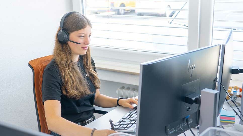 Azubi Industriekaufman: Die Auszubildende Laura von Genkinger telefoniert am Headset und macht sich während eines Gesprächs Notizen auf einem Block an ihrem Arbeitsplatz.