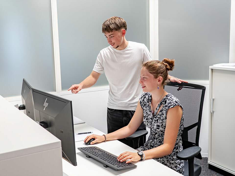 Industriekaufmann: Die Auszubildenden Ramon und Laura von Genkinger arbeiten gemeinsam an einem Computerarbeitsplatz und bearbeiten kaufmännische Aufgaben während ihrer Ausbildung.