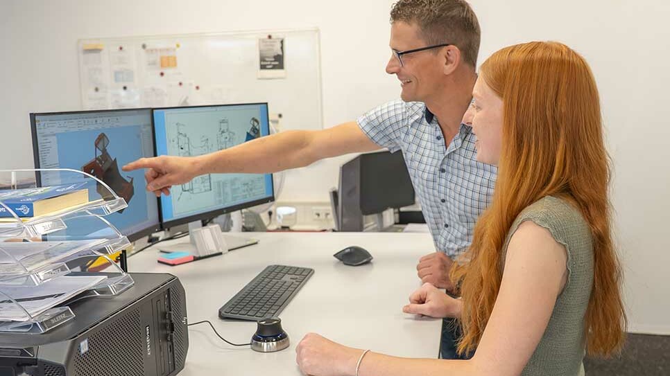 Ausbilder bespricht mit Auszubildender zur Technischen Produktdesignerin eine Konstruktion am Computer