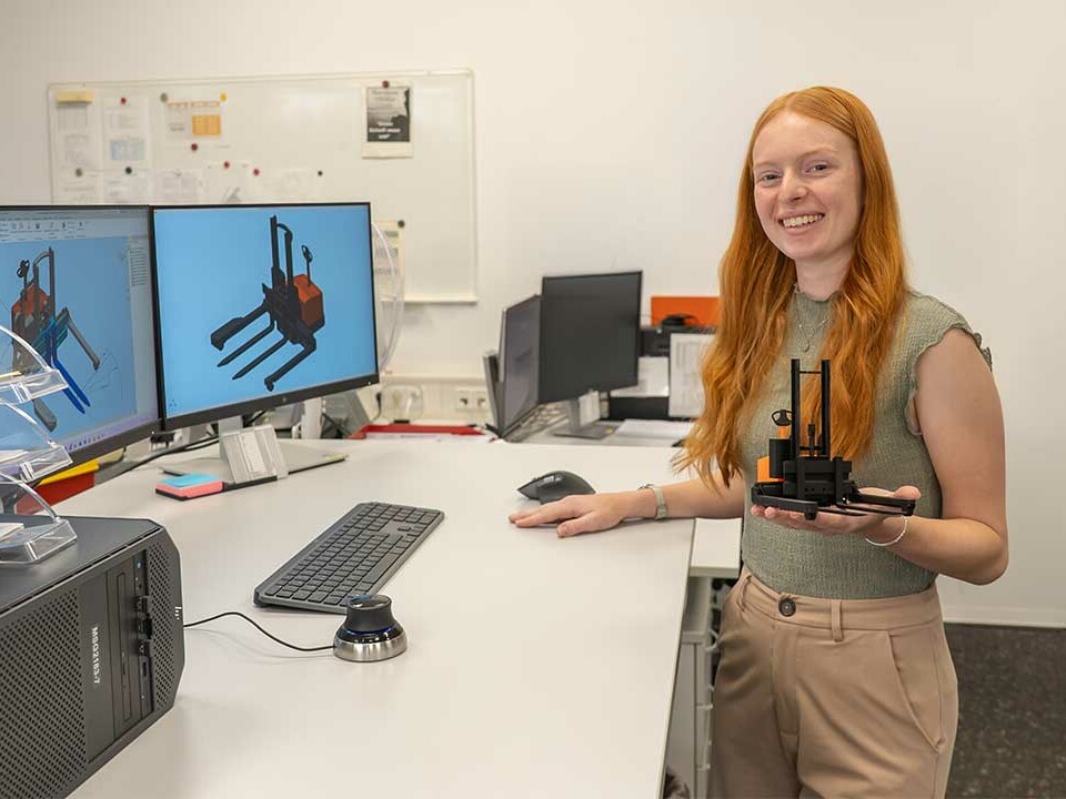 Auszubildende Technische Produktdesignerin hält ein 3D-Druckmodell eines Flurförderzeugs von Genkinger