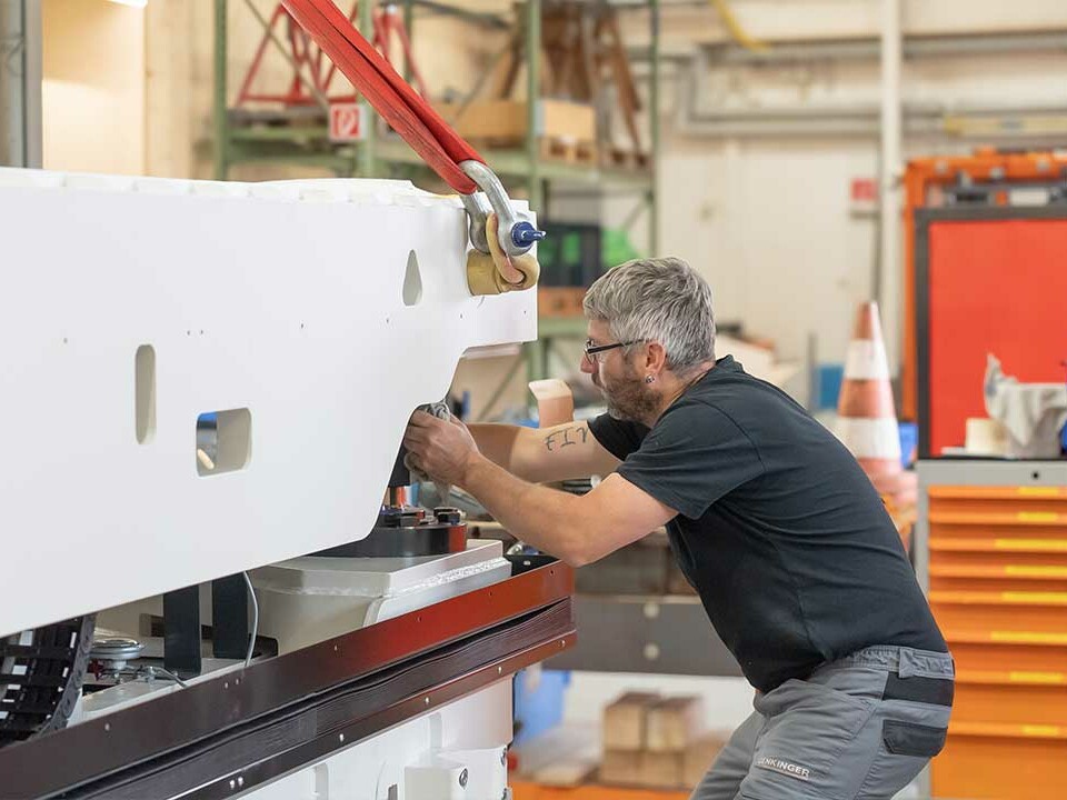 Mechaniker richten zwei Fahrzeugteile präzise aus und verbinden sie bei der Montage eines Flurförderzeugs.
