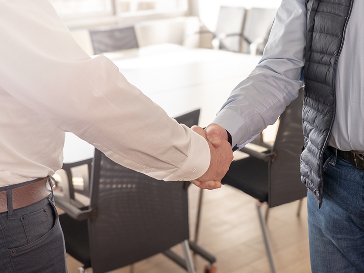 Handschlag zwischen einem Service-Mitarbeiter von Genkinger und einem Kunden als Symbol f&uuml;r eine abgeschlossene Service-Vereinbarung zur Wartung und Instandhaltung von Maschinen.